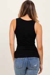 woman wearing a fitted black ribbed tank top and light blue distressed jeans, viewed from the back
