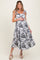 woman wearing a floral print maternity dress with shoulder ties, showcasing her baby bump, styled with wedge sandals