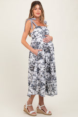 woman wearing a floral maternity dress with tie straps and pockets, showcasing her baby bump