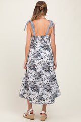 woman wearing a floral print maternity dress with back tie details and a flowing skirt