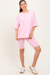 woman wearing a pink oversized t-shirt with pocket and matching pink bike shorts, styled with white sneakers