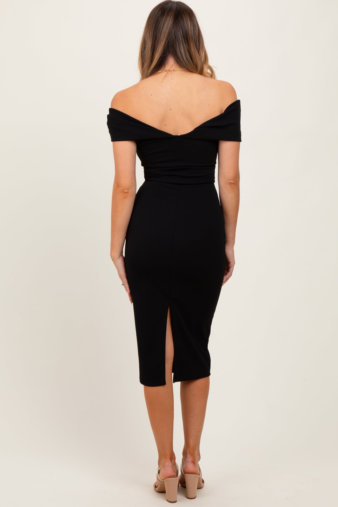woman wearing a black off-the-shoulder midi dress with a slit at the back