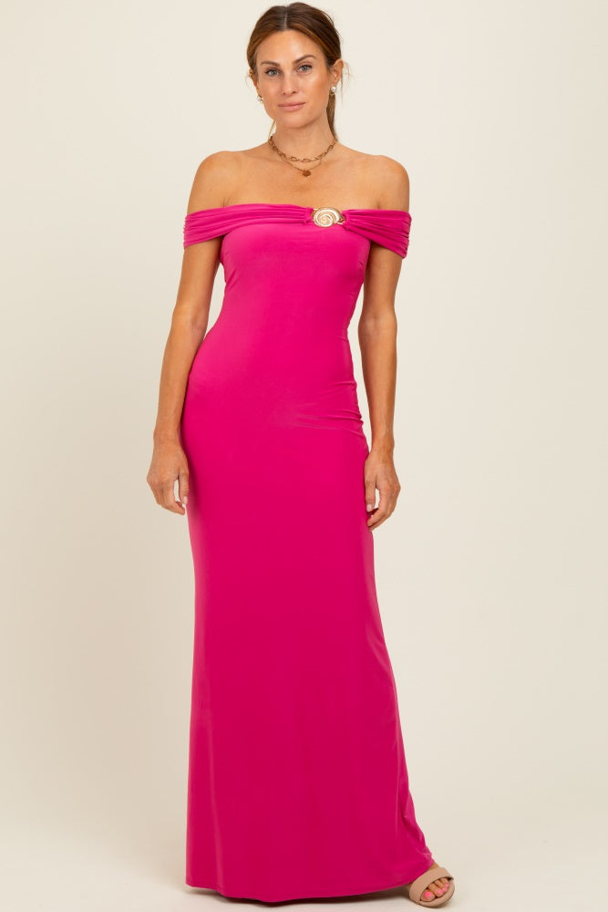 woman wearing a vibrant pink off-the-shoulder evening gown with ruched detailing and a gold emblem on the bust