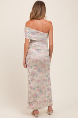 woman wearing a pastel floral off-the-shoulder maternity maxi dress, showing her baby bump from the back