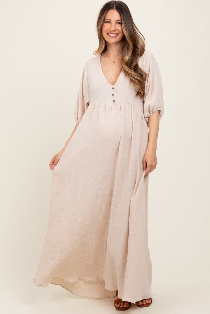 woman wearing a beige long sleeve maternity maxi dress with buttons and a visible baby bump