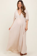 woman wearing a beige long sleeve maternity maxi dress with buttons and a visible baby bump