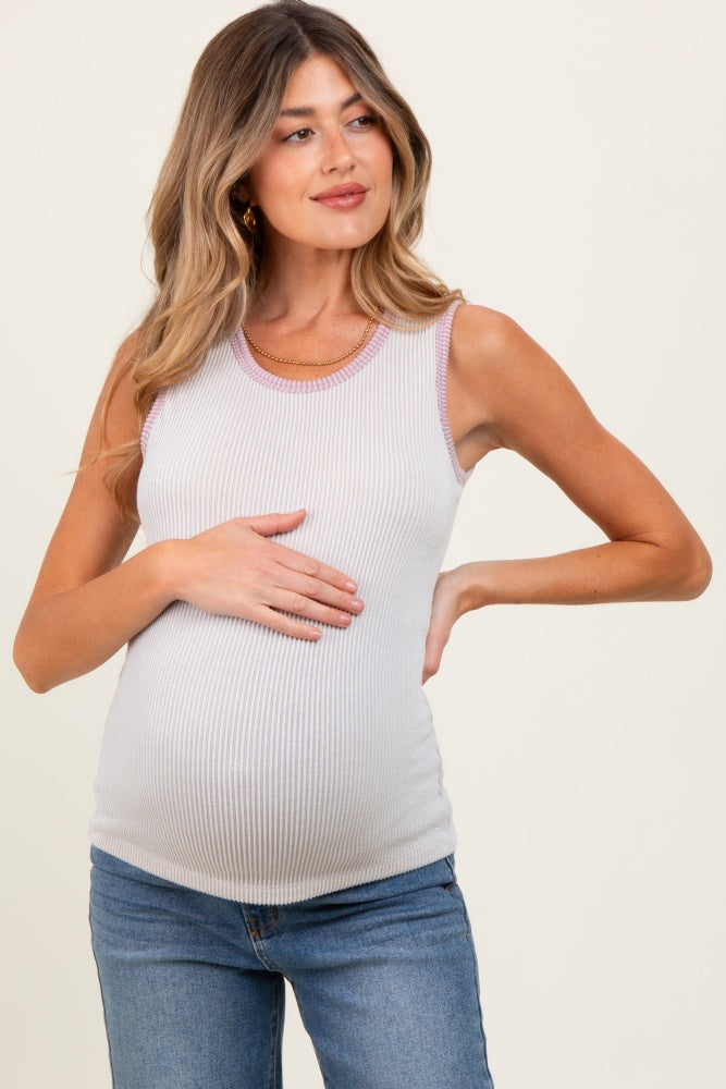 woman wearing a light gray maternity tank top with a ribbed texture and pink trim, holding her baby bump