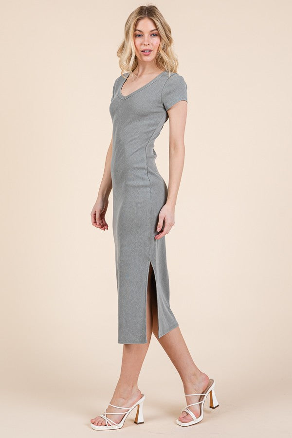 woman wearing a fitted gray midi dress with short sleeves and a side slit, paired with white heeled sandals