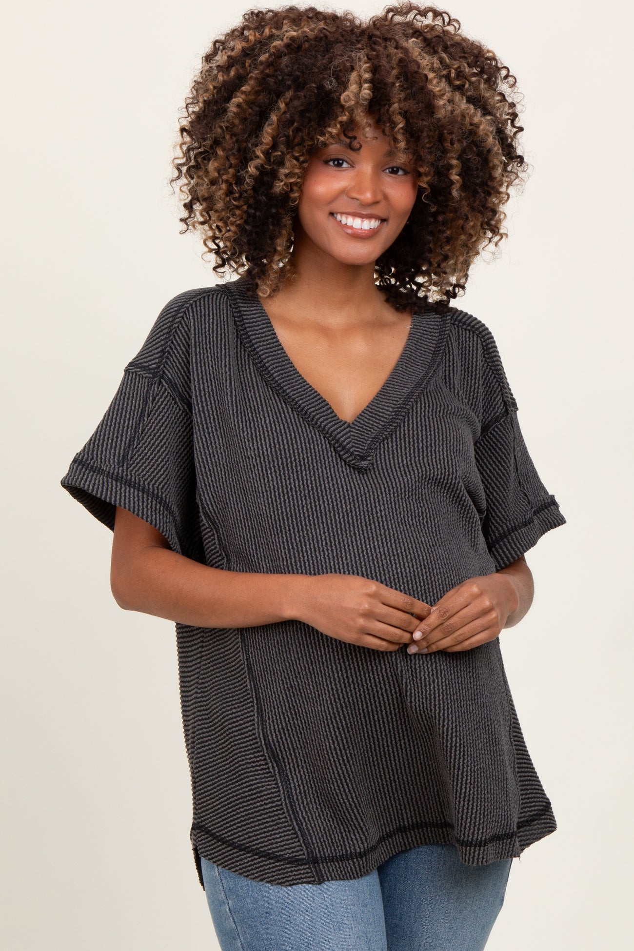 woman wearing a black and white striped maternity top with a v-neck and short sleeves, holding her baby bump