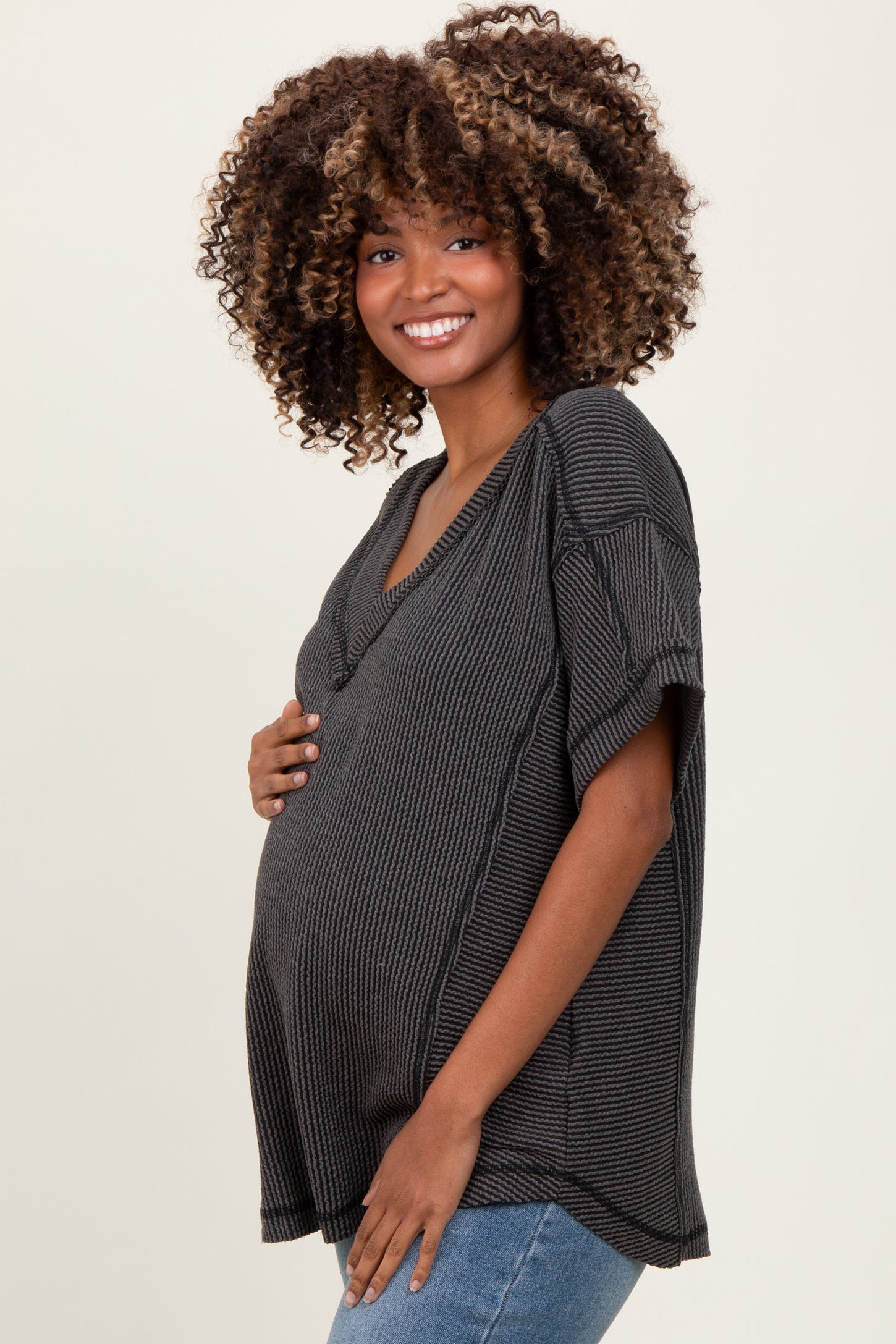 woman wearing a dark gray ribbed maternity top and holding her baby bump
