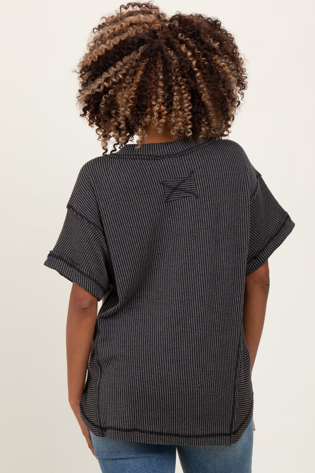 woman wearing a black and gray striped maternity top, styled with short sleeves and a relaxed fit