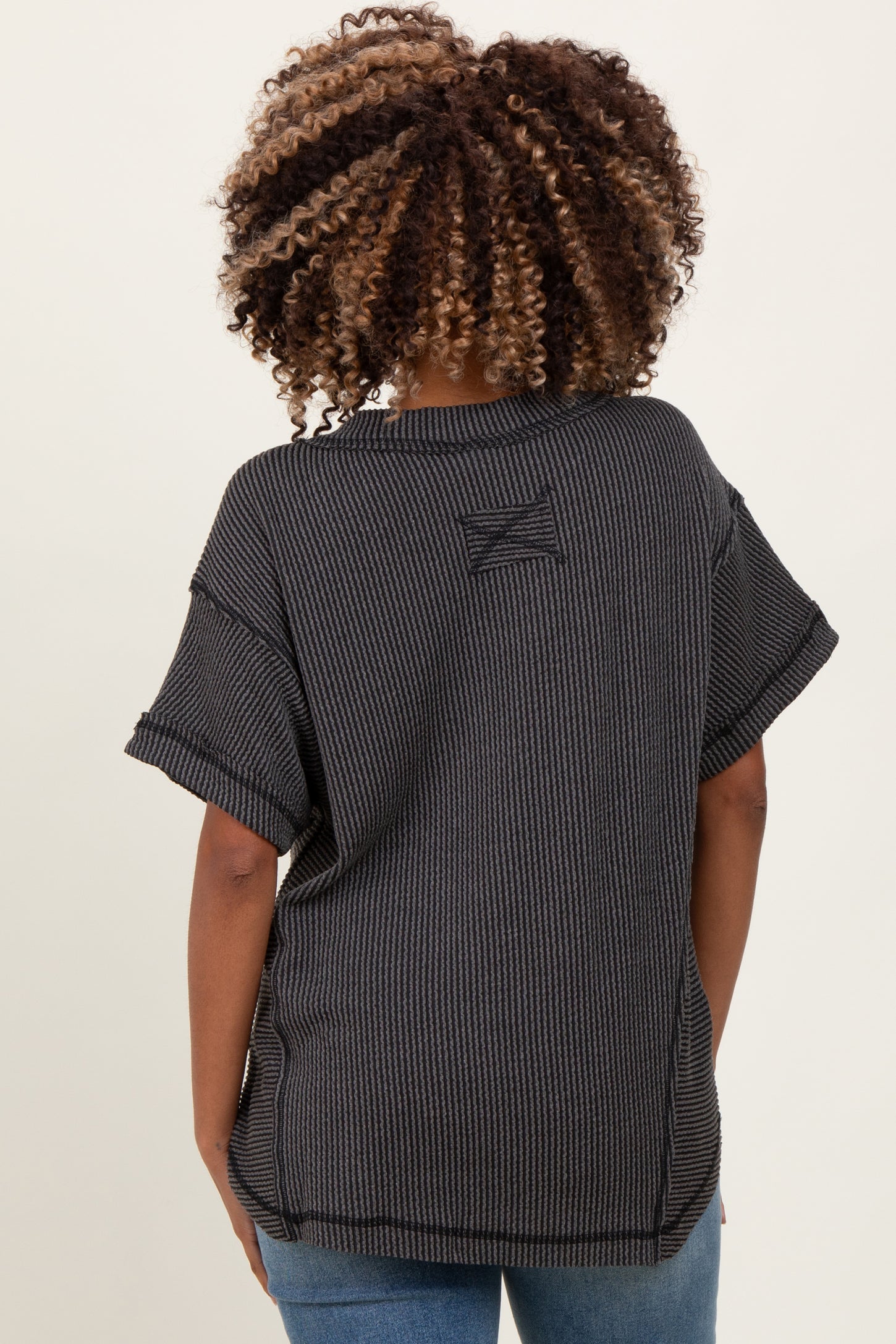 woman wearing a black and gray striped maternity top, styled with short sleeves and a relaxed fit