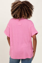 woman wearing a pink oversized maternity top with short sleeves and a relaxed fit, seen from the back