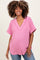 woman wearing a pink short sleeve textured maternity top and showing her baby bump