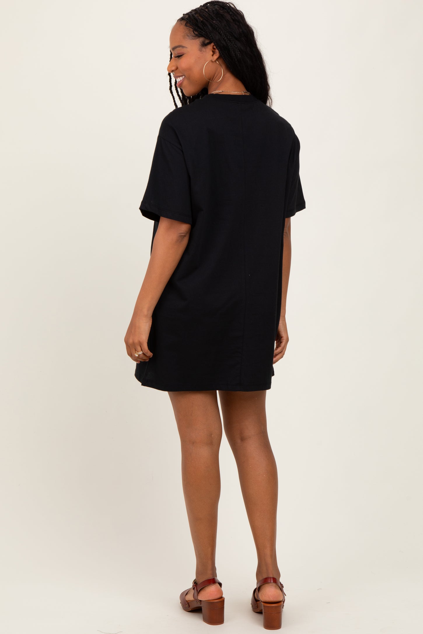 woman wearing a black oversized t-shirt dress with short sleeves, viewed from the back