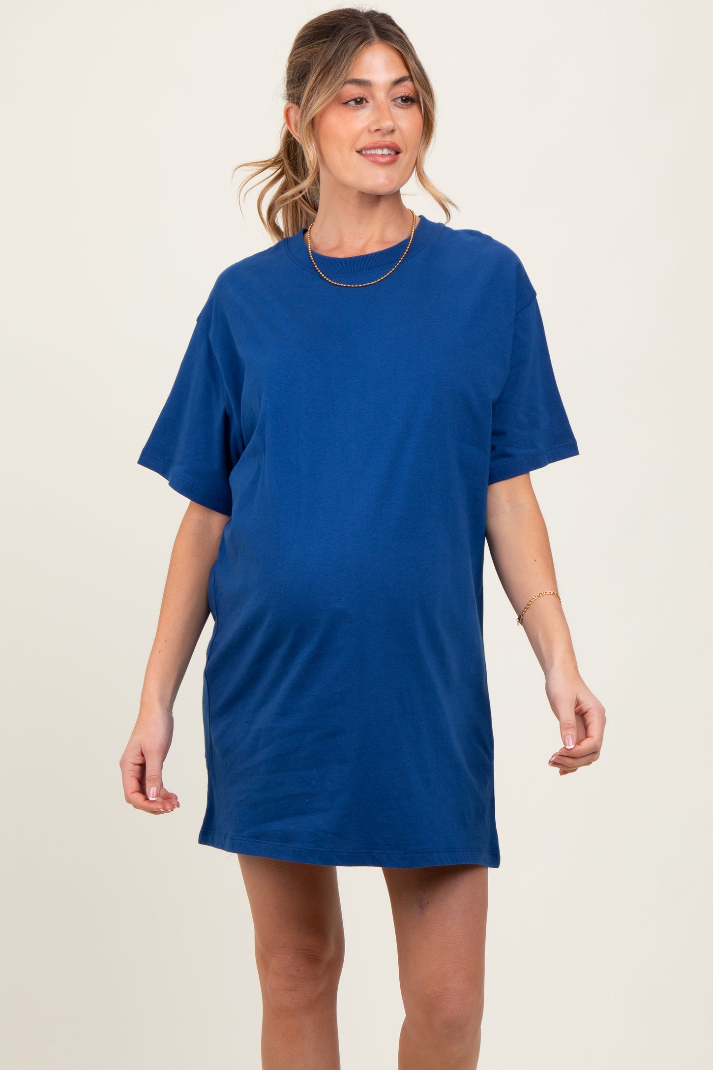 woman wearing a blue short sleeve maternity t-shirt dress with a visible baby bump