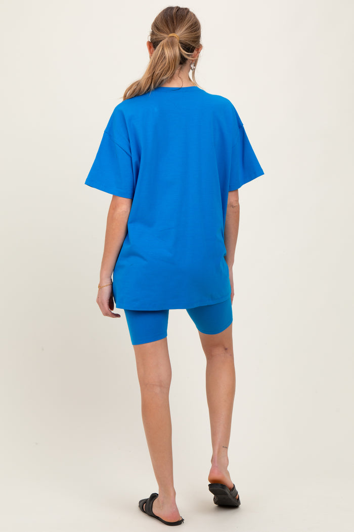 woman wearing a bright blue oversized t-shirt and matching biker shorts, showing a casual maternity look