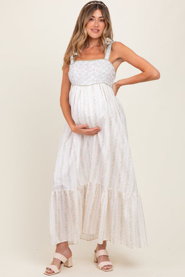 woman wearing a floral print maternity maxi dress with tied straps and holding her baby bump