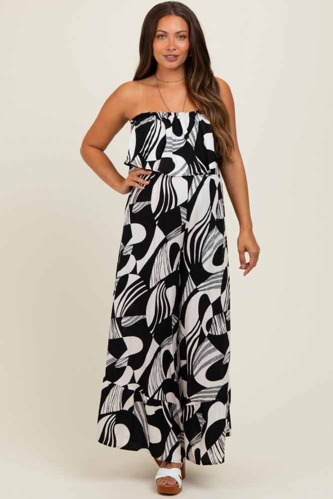 woman wearing a black and white patterned maternity maxi dress with a ruffled neckline and wide leg style