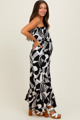 woman wearing a black and white patterned maternity maxi dress with pockets and a ruffled hem, showing her baby bump