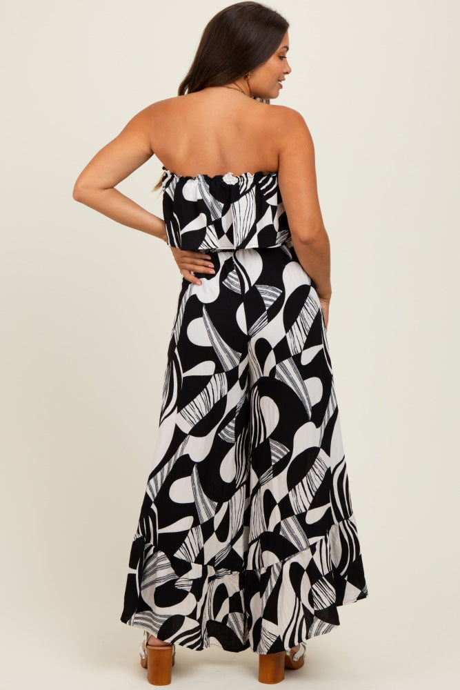 woman wearing a black and white printed strapless maternity jumpsuit with a flowy design and ruffled hem