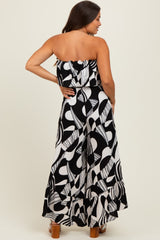 woman wearing a black and white printed strapless maternity jumpsuit with a flowy design and ruffled hem