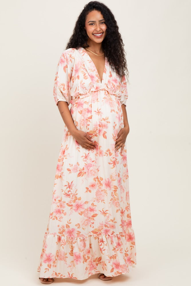 woman wearing a floral maternity maxi dress with puff sleeves and a v-neck, showcasing her baby bump