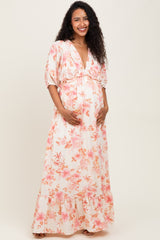 woman wearing a floral maternity maxi dress with puff sleeves and a v-neck, showcasing her baby bump