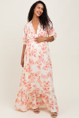 woman wearing a floral maternity maxi dress with a deep v-neck and a flowing skirt, gently holding her baby bump