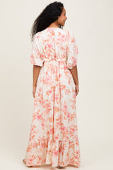 woman wearing a floral patterned maternity maxi dress with a ruffled hem and puff sleeves, showing her baby bump
