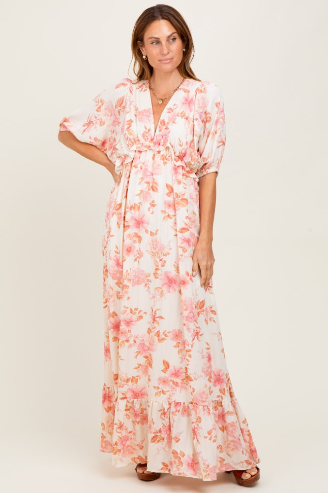 woman wearing a white floral maxi dress with pink flowers and short sleeves, featuring a cinched waist and ruffled hem