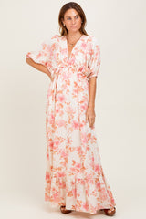 woman wearing a white floral maxi dress with pink flowers and short sleeves, featuring a cinched waist and ruffled hem