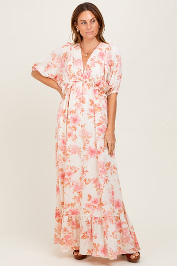 woman wearing a white floral maxi dress with pink flowers and short sleeves, featuring a cinched waist and ruffled hem