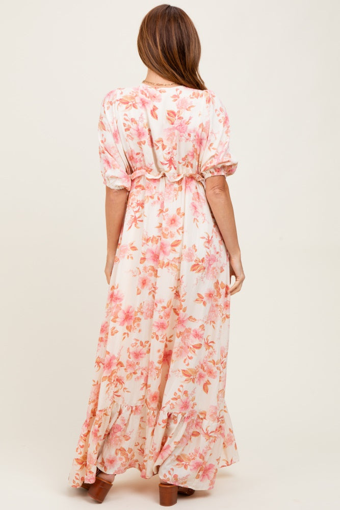 woman wearing a long floral maxi dress with pink and peach blooms and a cinched waist, seen from the back