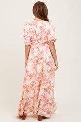 woman wearing a long floral maxi dress with pink and peach blooms and a cinched waist, seen from the back