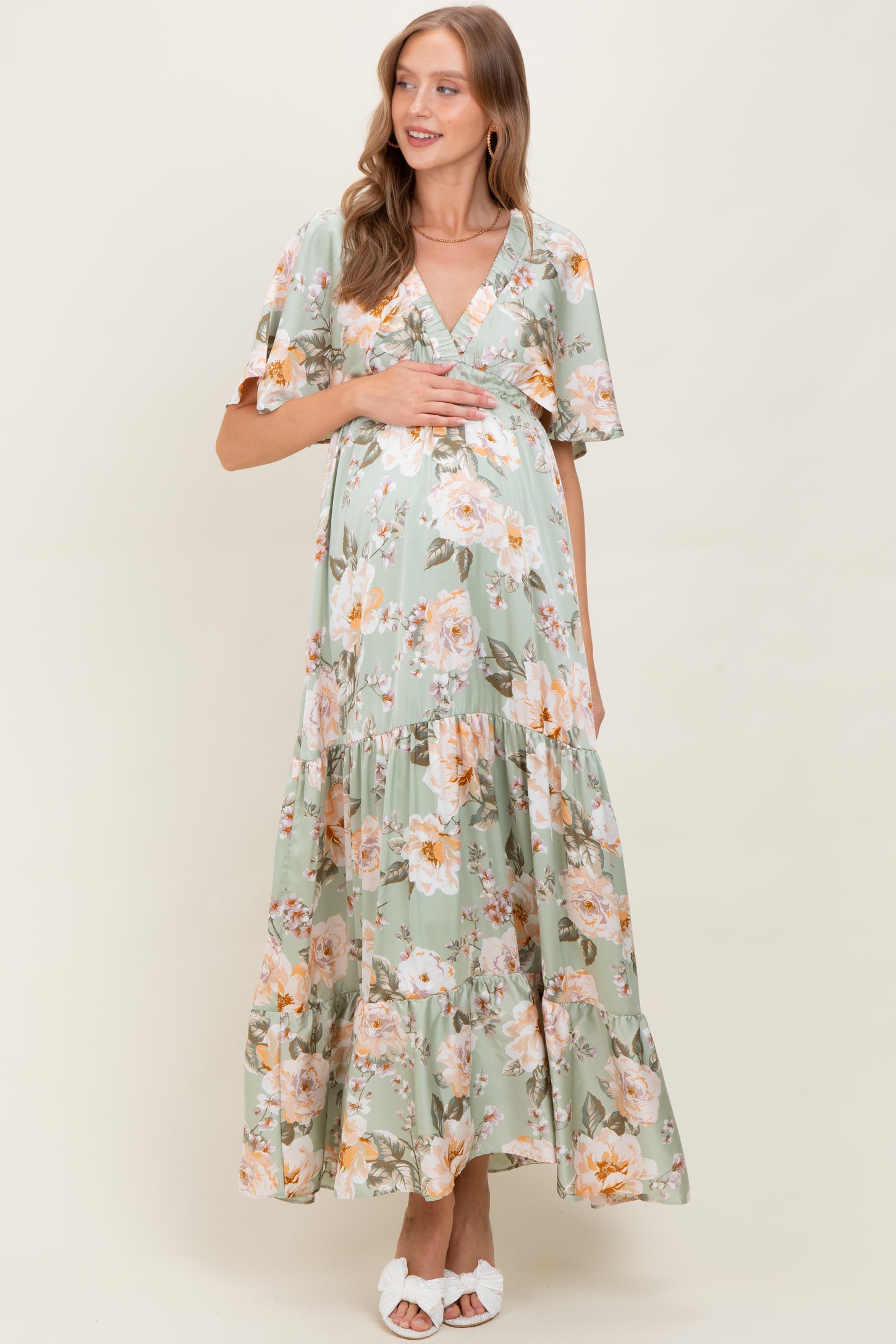 woman wearing a floral green maternity maxi dress and holding her baby bump