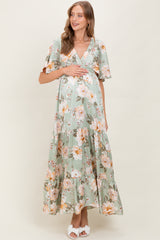 woman wearing a floral green maternity maxi dress and holding her baby bump