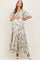 woman wearing a floral print green maternity maxi dress and holding her baby bump