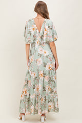 woman wearing a floral green maternity maxi dress with ruffled sleeves and a v-back, showing a baby bump