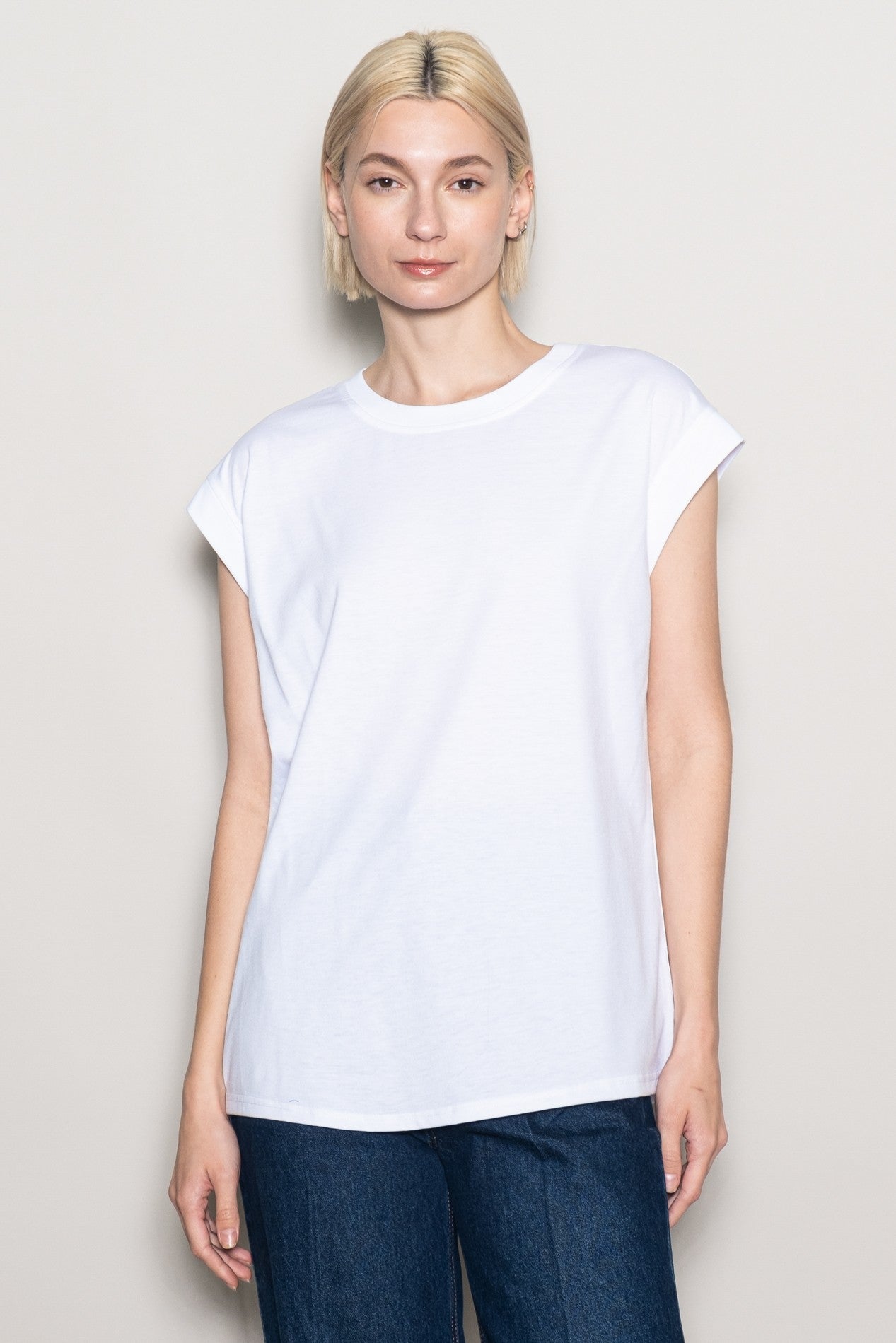 woman wearing a white short sleeve t-shirt with rolled cuffs and a relaxed fit, paired with blue denim jeans