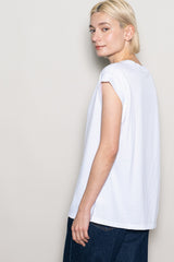 woman wearing a white casual t-shirt with rolled sleeves, featuring a relaxed fit and styled with dark blue jeans