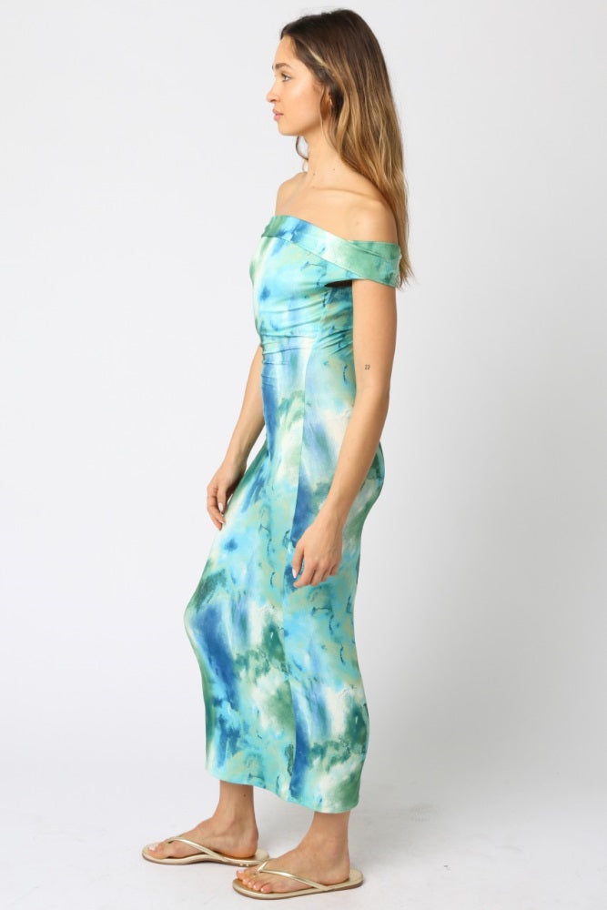 woman wearing a green and blue tie-dye off-shoulder maxi dress standing sideways