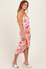 woman wearing a colorful floral wrap midi dress and white block-heeled sandals