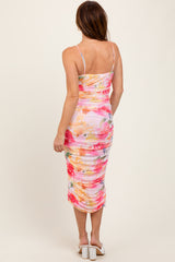woman wearing a multicolored floral print bodycon dress with ruching and thin spaghetti straps, seen from the back