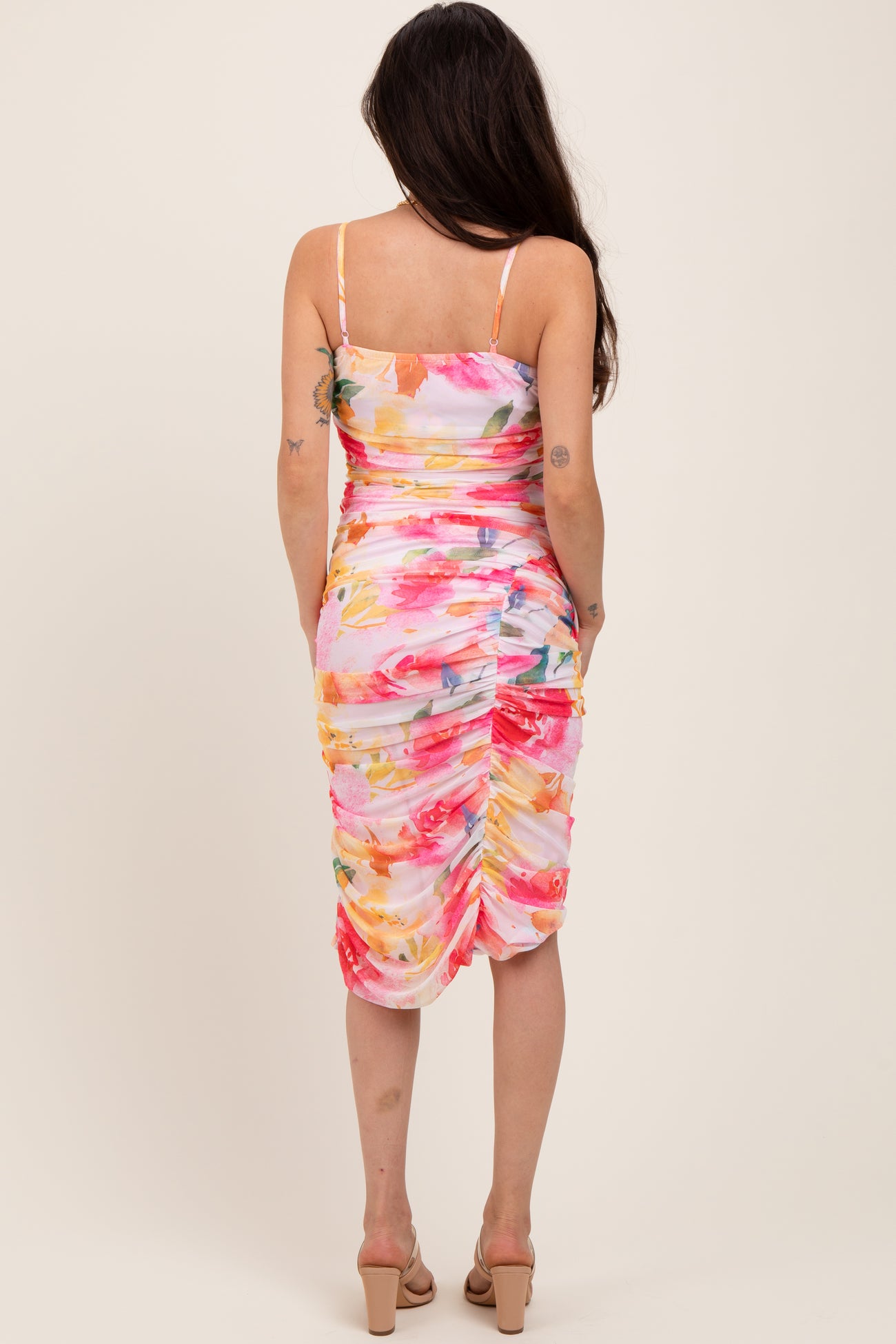 woman wearing a floral print maternity dress with ruched detailing, showing a baby bump from the back
