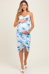 woman wearing a blue and white floral print maternity dress and holding her baby bump