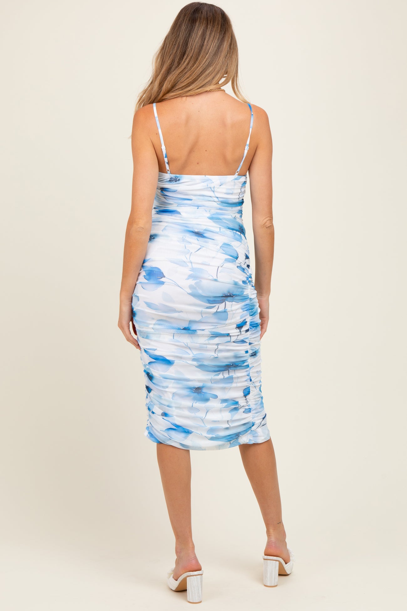 woman wearing a blue and white floral maternity dress with ruching and spaghetti straps, showing off her baby bump