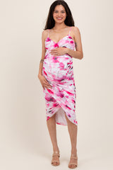 woman wearing a floral pink maternity dress, holding her baby bump with a ruched design and side slit