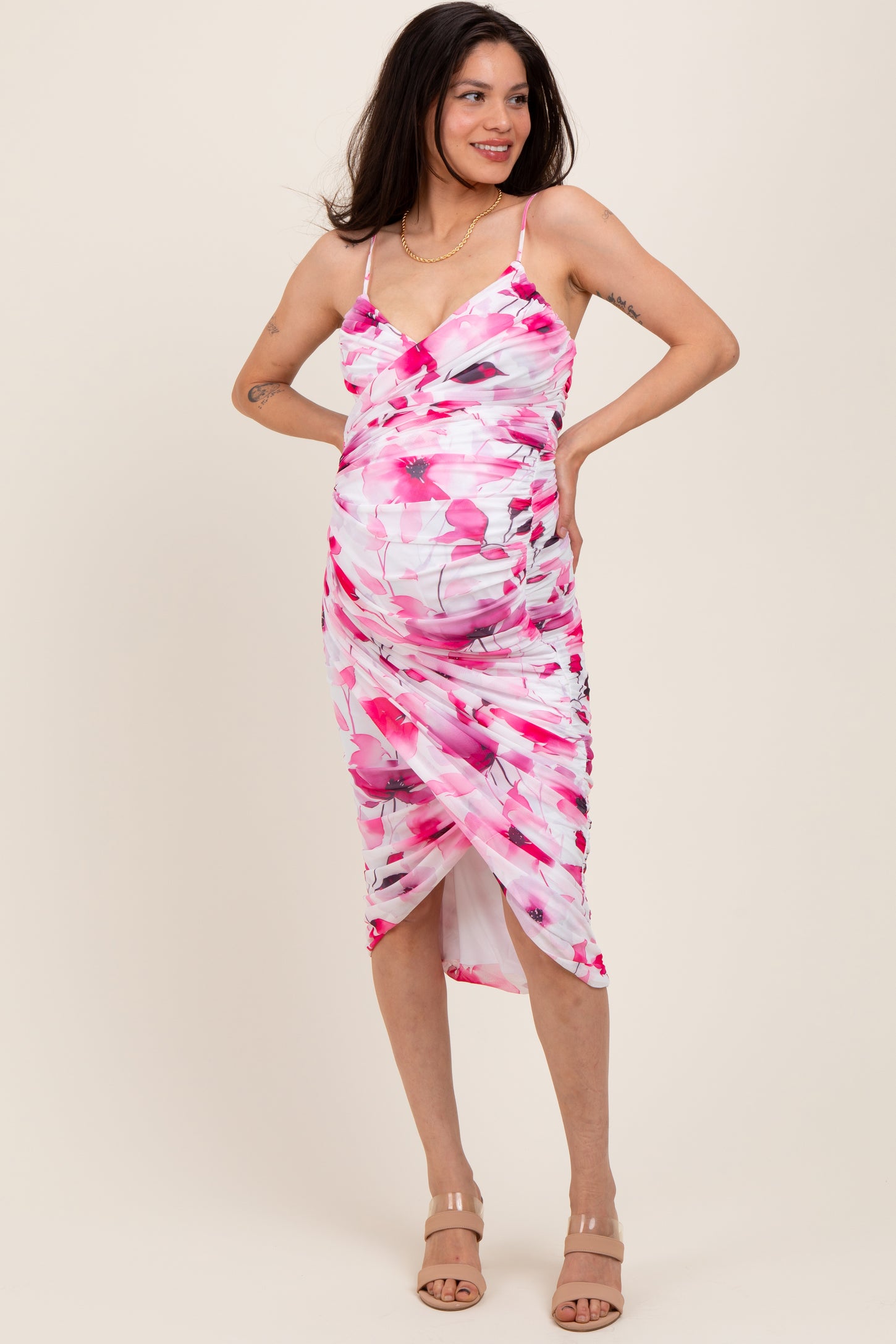 woman wearing a pink and white floral maternity dress with ruching, showing off her baby bump
