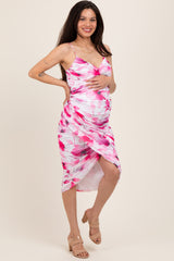 woman wearing a pink floral maternity dress with a side slit and holding her baby bump